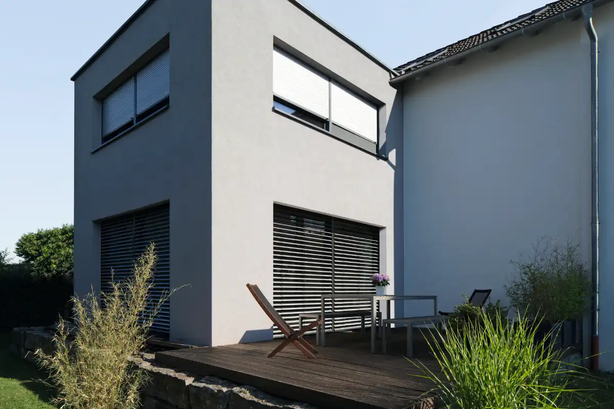 Haus mit Rolläden und einer stilvoller Terrasse Moderne Terrasse mit Sitzgelegenheit und Sonnenschutz