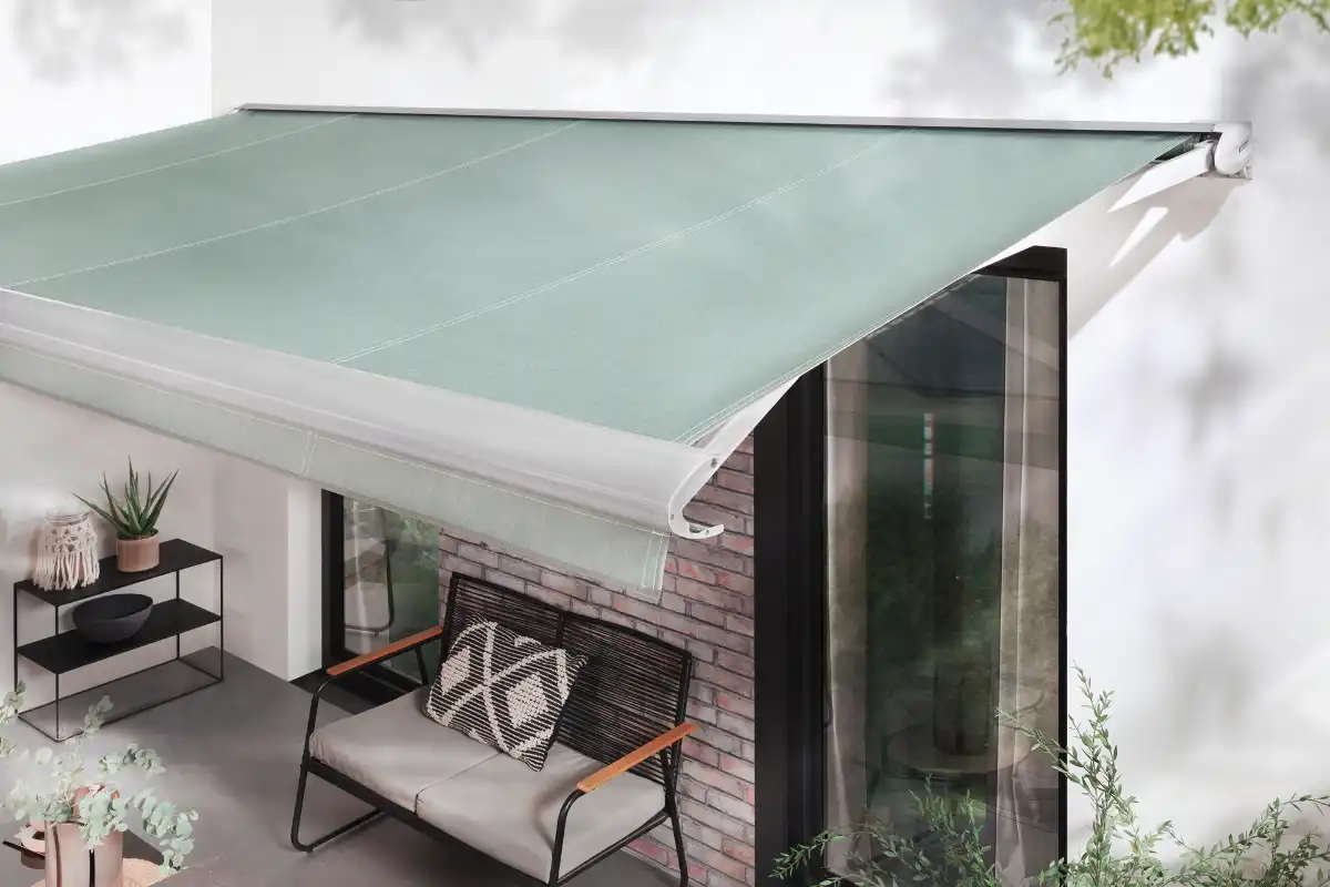 Moderne grüne Markise über einer Terrasse mit gemütlichem Sitzbereich